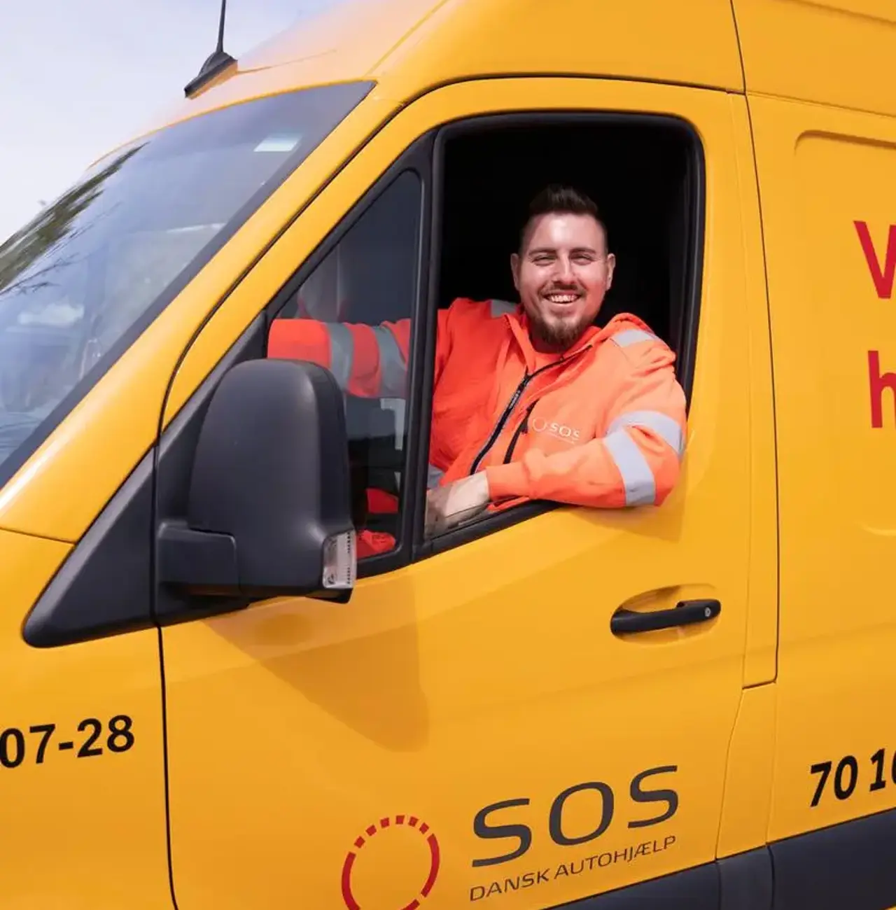 Autoredder sidder i teknikerbil og smiler