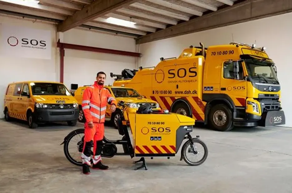 Autoredder står ved elcykel. I baggrunden ses forskellige vejhjælpsbiler