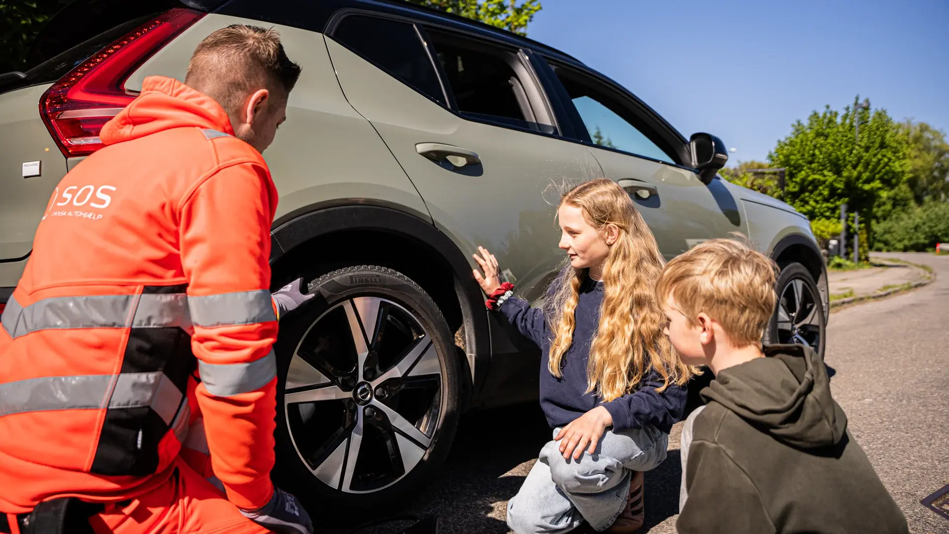Børn sidder ved siden af bil med autoredder