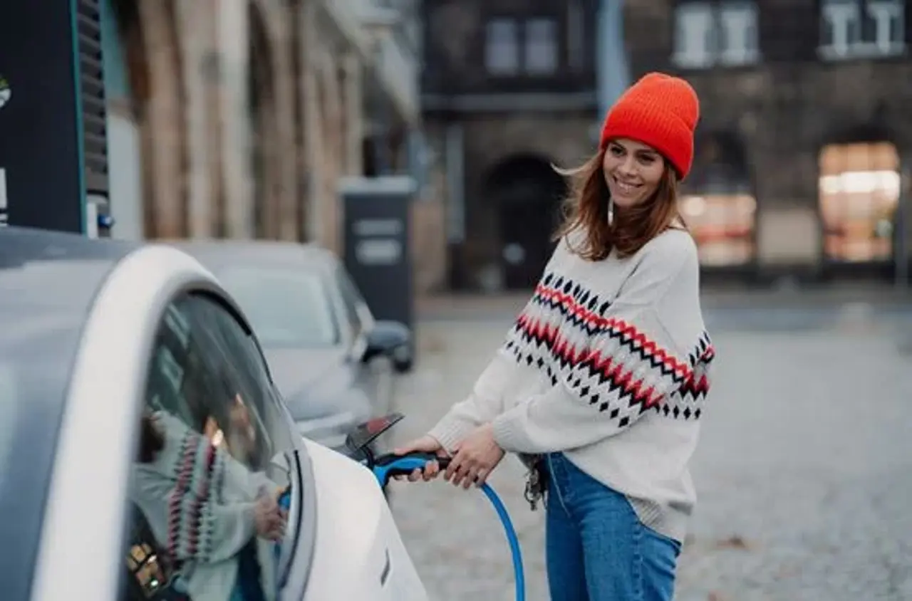 Dame sætter elkabel i bil
