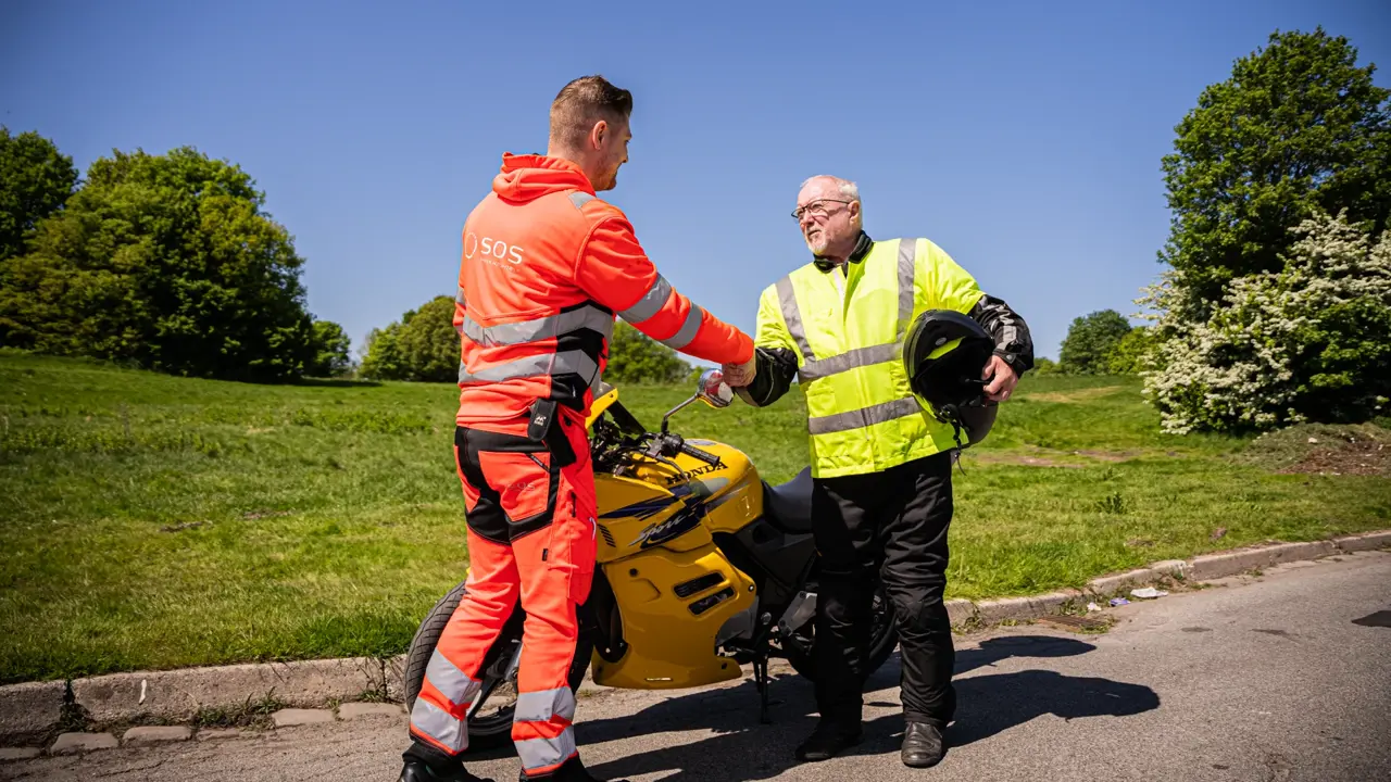 Autoredder og motorcykellist giver hånd