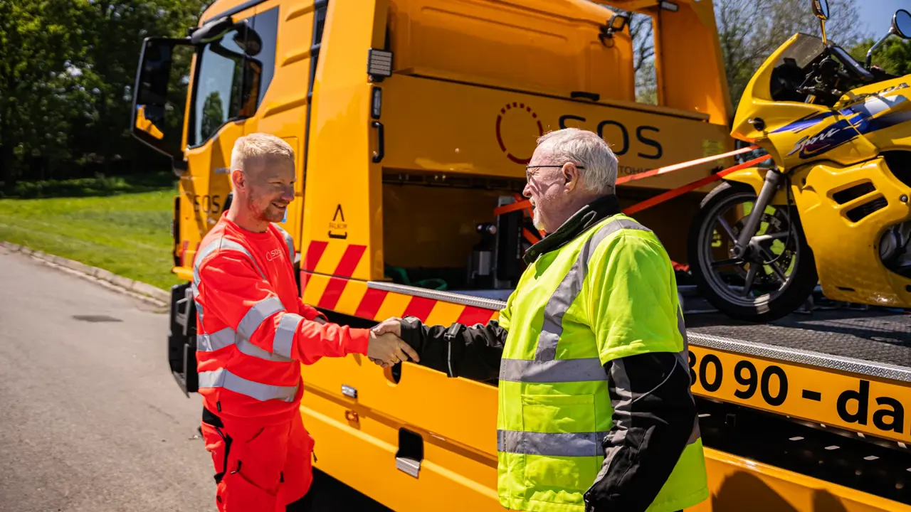 Autoredder og motorcykel ejer giver hånd