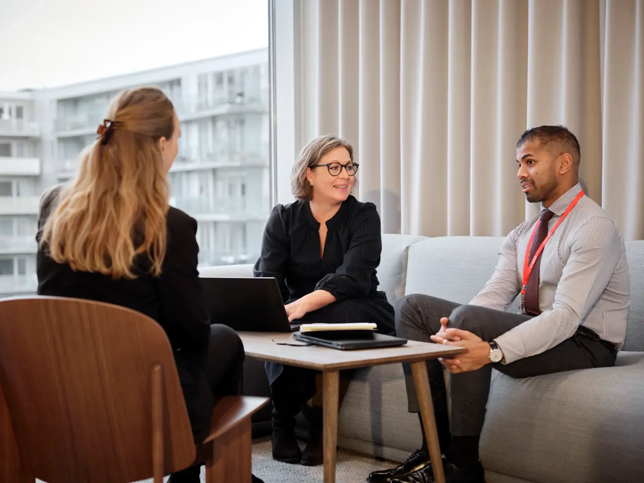 tre personer sitter i en soffgrupp på jobbet