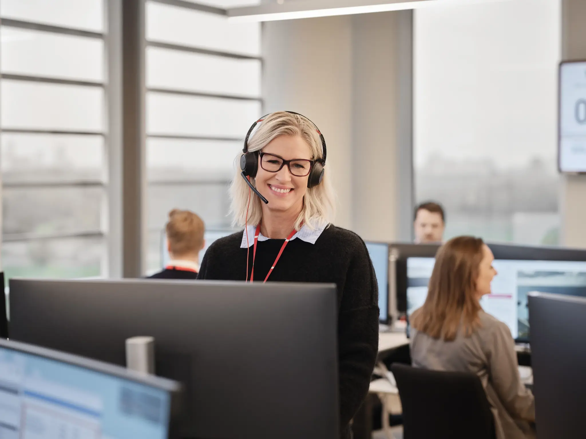 Kvinne med headset i alarmsentral ved en datamaskin