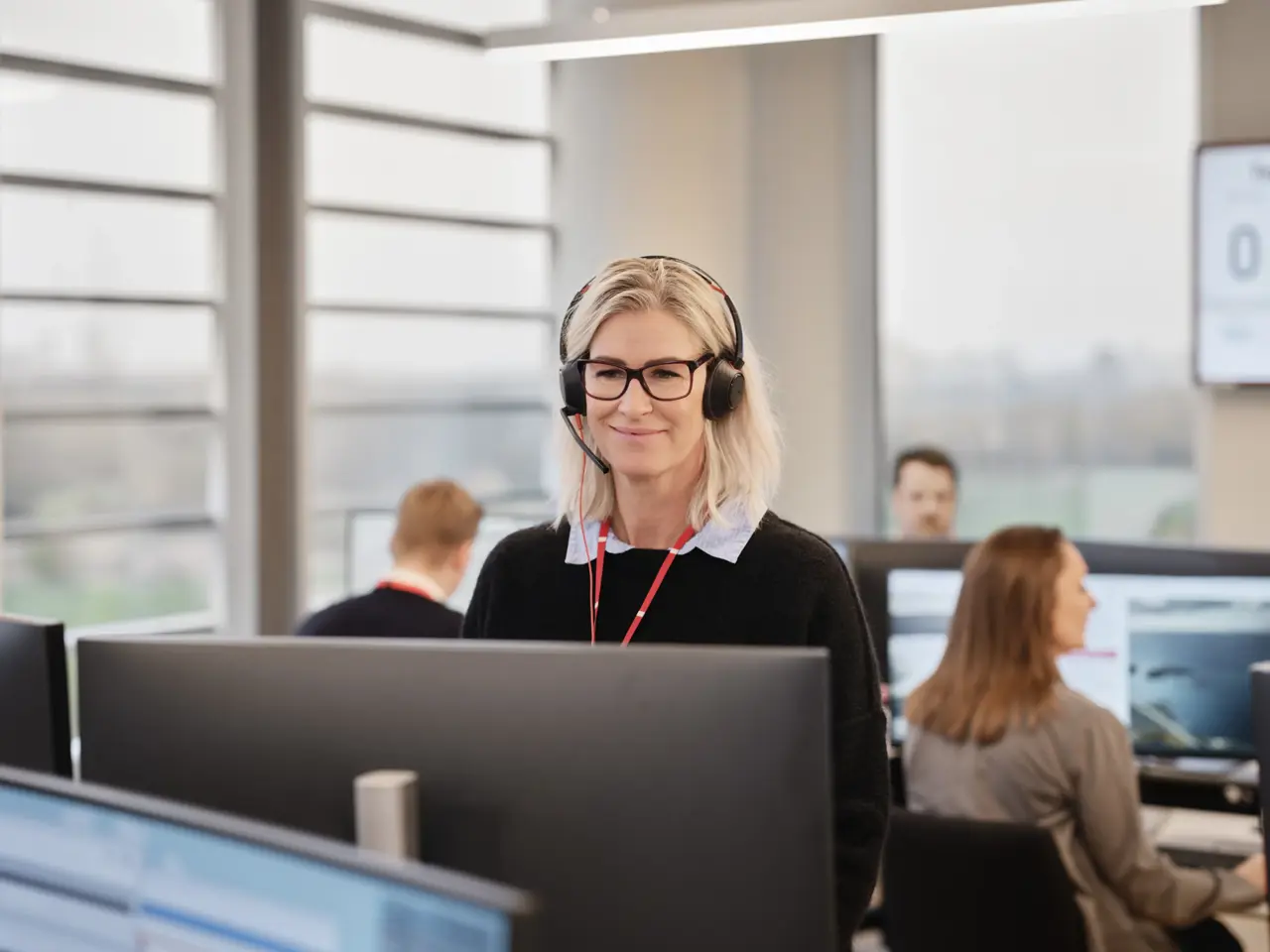 Kvinne med headset ser på PC