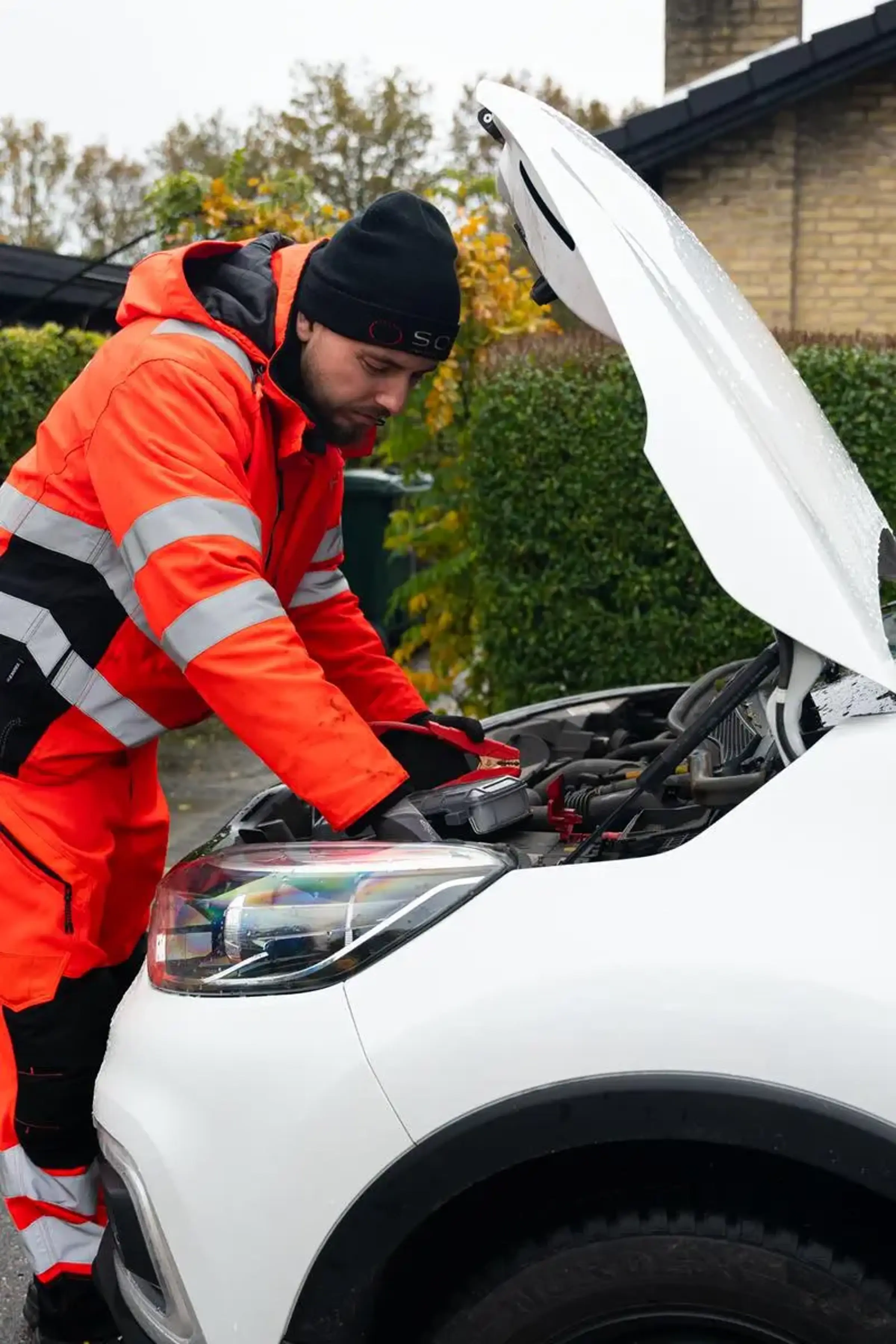 Closeup af autoredder der står og er i gang med at genstarte bil med booster