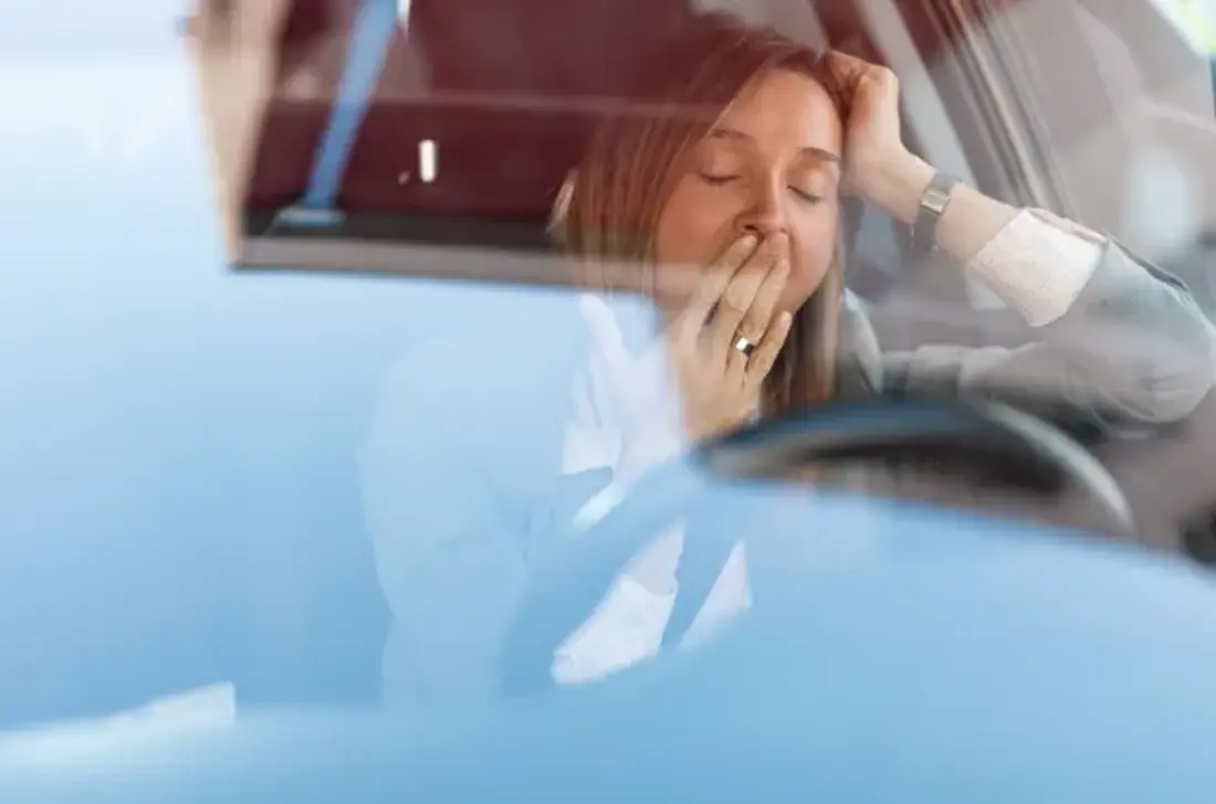 Trött kvinna bakom ratten i en bil