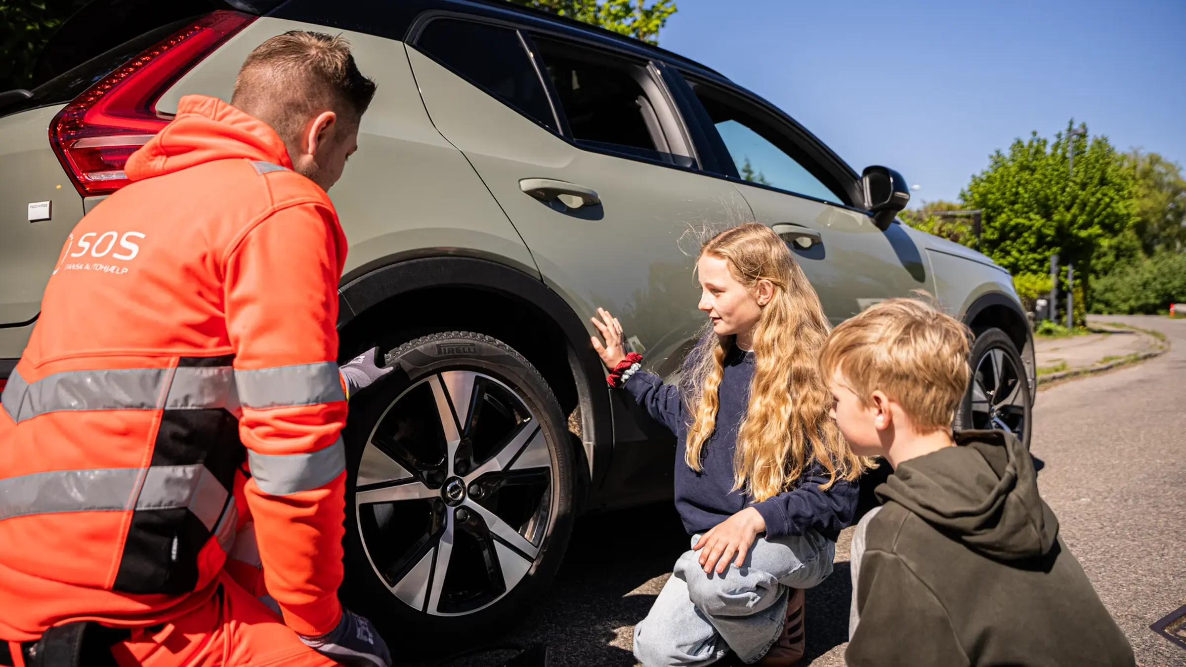 Børn sidder ved siden af bil med autoredder