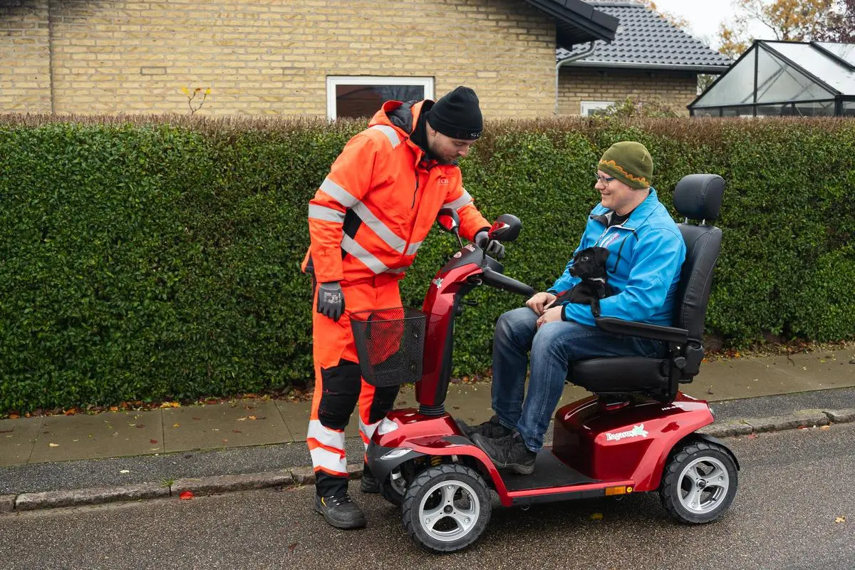 Autoredder står med hånden på elscooter 