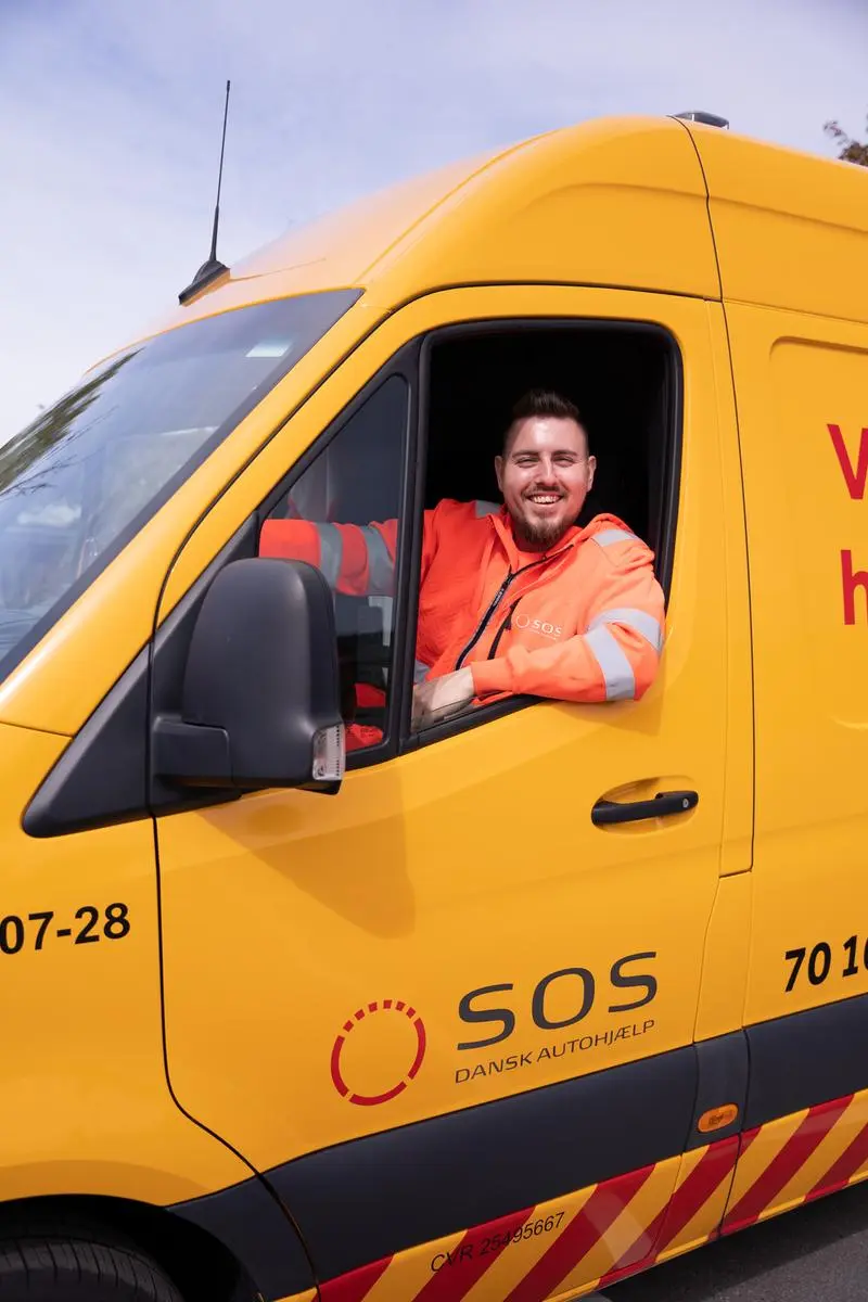 Autoredder sidder i teknikerbil og smiler