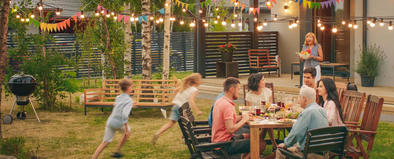 Kids running in the yard while the family eats outside