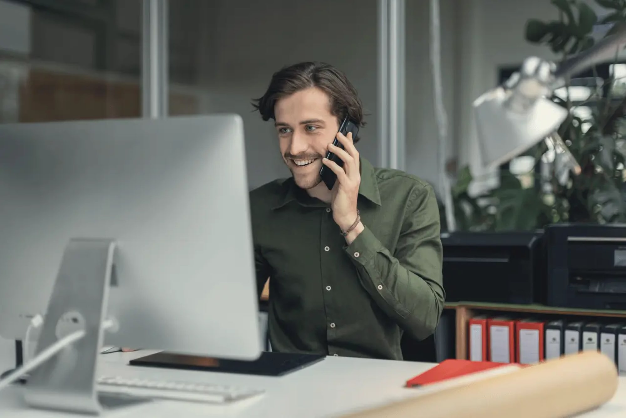 Geschäftsmann mit Smartphone am Schreibtisch