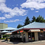 Abc Country restaurant in front of Accent Inns with a blue roof and a blue sky with white clouds in the background and trees in the foreground.