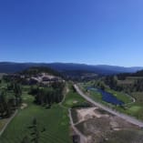 Aerial view of Black Mountain Golf Club in Kelowna, featuring golf courses, greenery, and nearby landscapes under a clear blue sky.