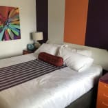 a bedroom with a bed, nightstands, and a painting on the wall behind the bedspread