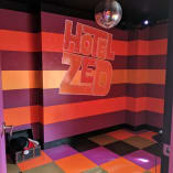 a brightly colored room with a disco ball hanging from the ceiling and a sign that reads hotel zed on the wall