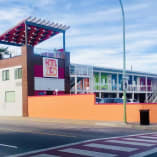 a red and white building on the side of a road with a red awning over its entrance.