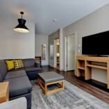 a living room filled with furniture and a flat screen tv mounted on a wall above a wooden coffee table at Hyatt Place Kelowna in Kelowna.