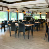 a dining room with tables and chairs and a television on the wall above the fireplace in the center of the room