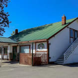 a white building with a green roof and a green roof and a staircase leading up to the second floor