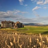 a golf course with a large building in the background and a field of tall grass in the foreground