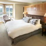 a bedroom with a large bed and a chair in front of a window with a view of the mountains at Predator Ridge Golf Resort