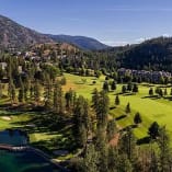 an aerial view of a golf course with a lake in the foreground and a mountain in the background