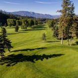 a view of a golf course with trees and a mountain in the background of the photo at Shannon Lake Golf Course, West Kelowna.