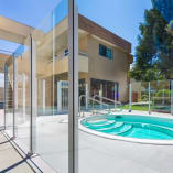 a swimming pool with a glass fence around it and a staircase leading up to the upper level of the house at Siesta Suites Kelowna in Kelowna.