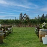 a bunch of barrels sitting on top of a lush green field next to a wooden structure with a triangle on top of it