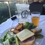 a white plate topped with a sandwich next to a glass of juice and a cup of tea on a table at Sunset Ranch Golf & Country Club in Kelowna