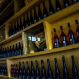 a wall full of bottles of wine in a wine cellar with a man in the window behind the bottles