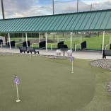 The Golf Centre Practice Facility in Kelowna with a green roof, putting green, and benches.