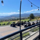 A view of a golf course from a hotel balcony at Tower Ranch Golf Club in Kelowna, with golf carts lined up and a beautiful landscape in the background.
