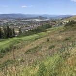 a view of a golf course from the top of a hill with a view of a valley and mountains in the distance at Tower Ranch Golf Club in Kelowna