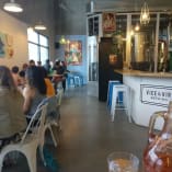 Busy interior of Vice & Virtue Brewing Co. in Kelowna with patrons seated at tables, modern industrial decor, and bright artworks on the walls.