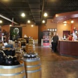 Interior view of the Volcanic Hills Estate Winery in West Kelowna with a tasting bar, wine displays, and customers.