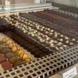 a display case filled with lots of different types of cakes and desserts on top of a white counter.