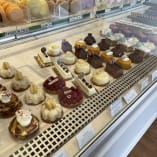 a display case filled with lots of different types of cakes and pastries in a pastry shop or bakery