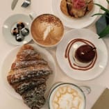 a white table topped with plates of food and a cup of coffee on top of a white table cloth