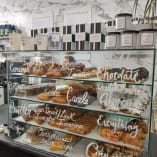 a display case filled with lots of different types of doughnuts and pastries in a bakery shop