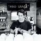 a woman working at a coffee shop with a coffee pot on the counter and a coffee pot on the counter in front of her