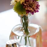 a vase filled with flowers sitting on top of a table next to two salt and pepper shakers on top of a table at Marmalade Cat Cafe in Kelowna