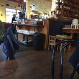 a restaurant with tables, chairs, and a man in a green shirt standing in front of the counter at Marmalade Cat Cafe in Kelowna