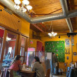 a couple of people sitting at a table in a room with yellow walls and a ceiling with metal piping