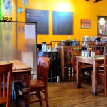 a restaurant with tables, chairs, and menus on the walls of the dining room and a bar in the back