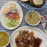 A table topped with plates of food next to a basket of soup and a plate of bread and a bowl of soup at Little Hobo Soup & Sandwich Shop in Kelowna.