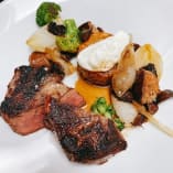 A plated dish from Old Vines Restaurant at Quail's Gate Winery in Kelowna, featuring seared steak, roasted vegetables, and a dollop of sauce.