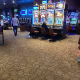 a casino room filled with lots of slot machines and people playing games on the machines and on the tables