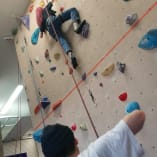 A man and a child are climbing up a rock wall with ropes and climbing gear on the side of the wall.